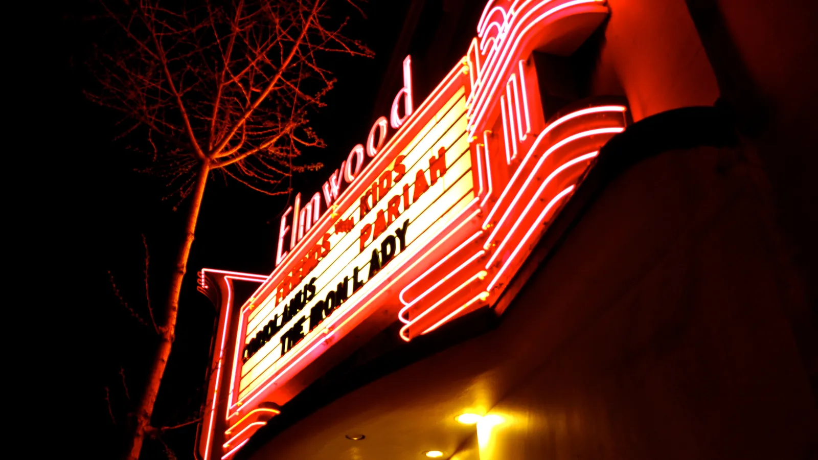 Rialto Cinemas Elmwood's red neon marquee glowing above College Avenue at night