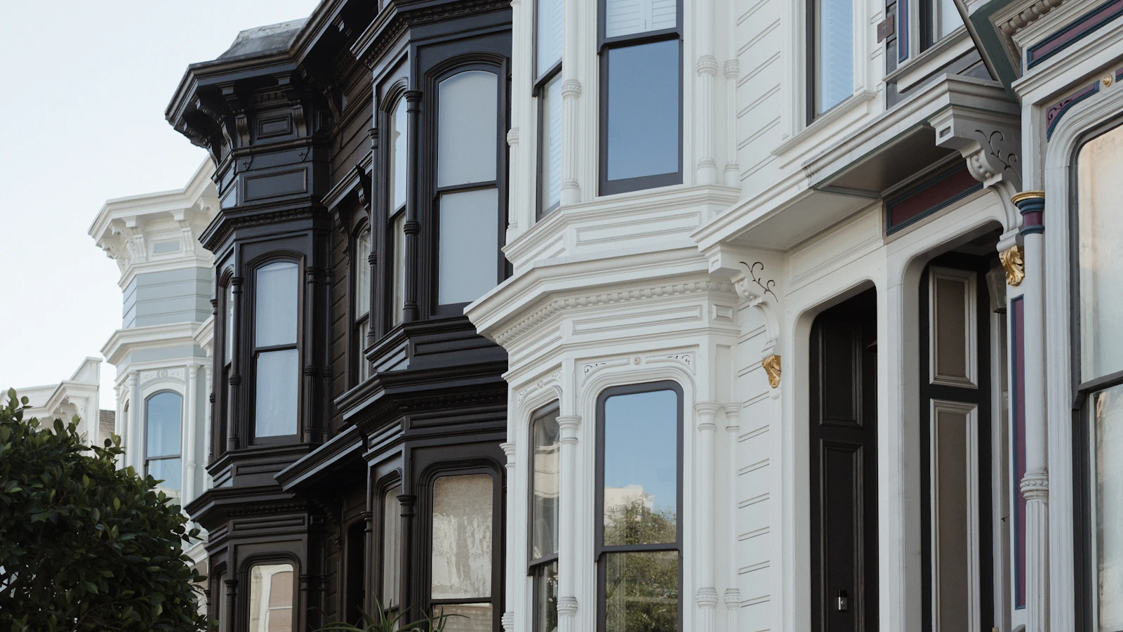 Closely spaced Victorian homes with bay windows and decorative exterior trim.