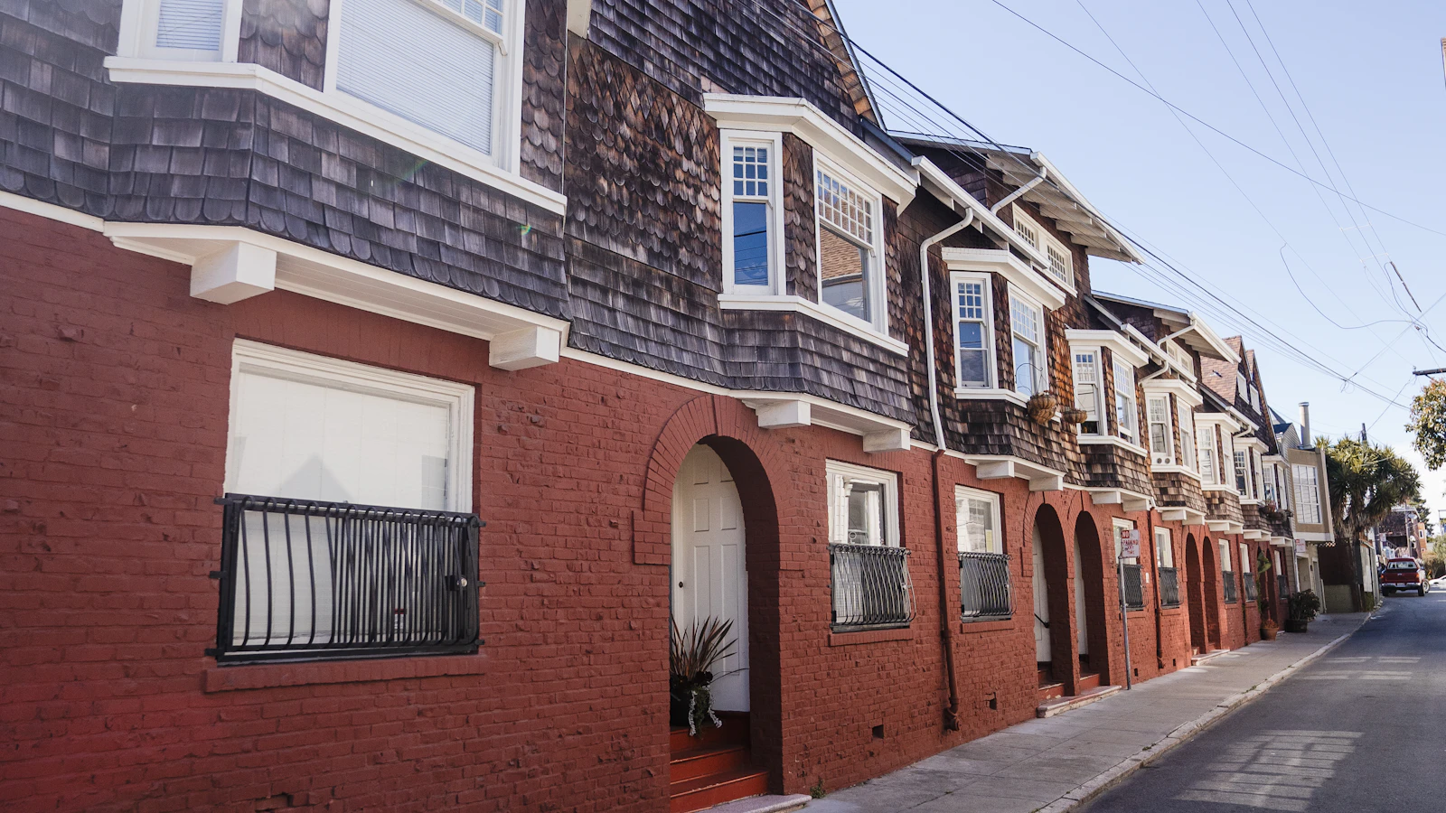 Homes with bay windows, shingled upper stories and red-brick ground-floor facades.